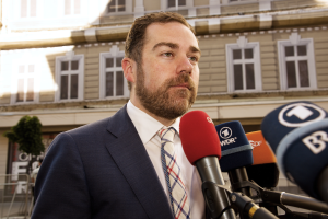 Ein Mann im Anzug und Krawatte steht vor Mikrofonen und spricht zur Presse vor einem Gebäude, wahrscheinlich wegen seiner dreijährigen Haftstrafe.