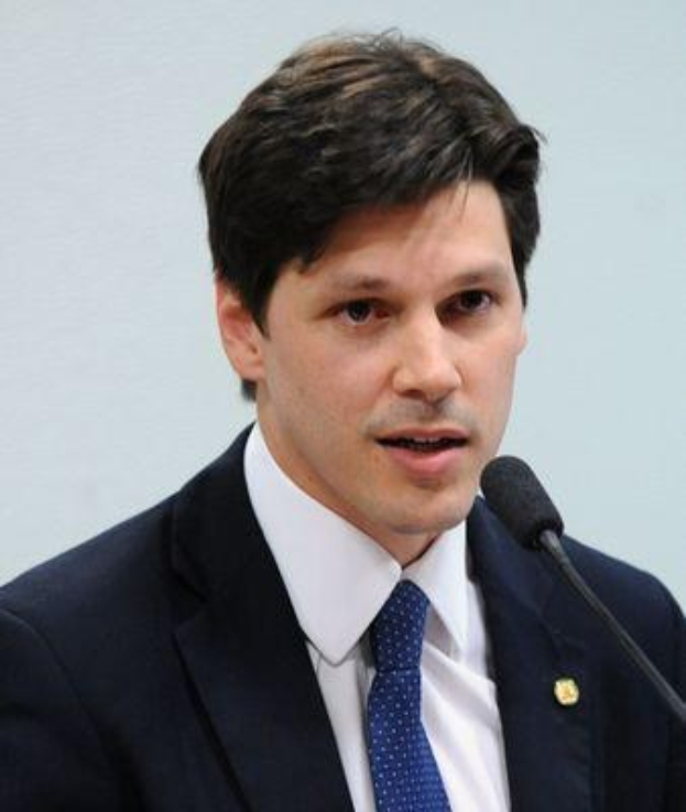 Ein Mann im Anzug spricht in ein Mikrofon an einem Podium, wahrscheinlich um die Genehmigung eines Gesetzes durch die Regierung zu kommentieren.