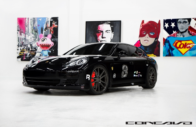 Ein schwarzer Nissan-Sportwagen ist vor Cartoon-Postern geparkt, mit einer kleinen Inschrift am unteren Rand des Bildes.