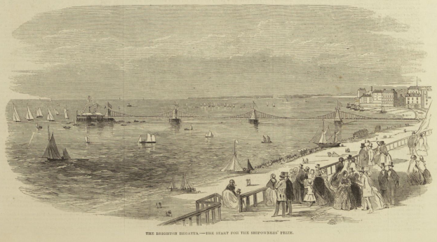 Eine Gruppe von Menschen, die auf einem Strand neben einem Gewässer mit Booten und einer Brücke im Hintergrund stehen, Gebäude auf der rechten Seite und Text unten mit der Aufschrift "The Brighton Regatta - The Start for the Shipowners Prize".