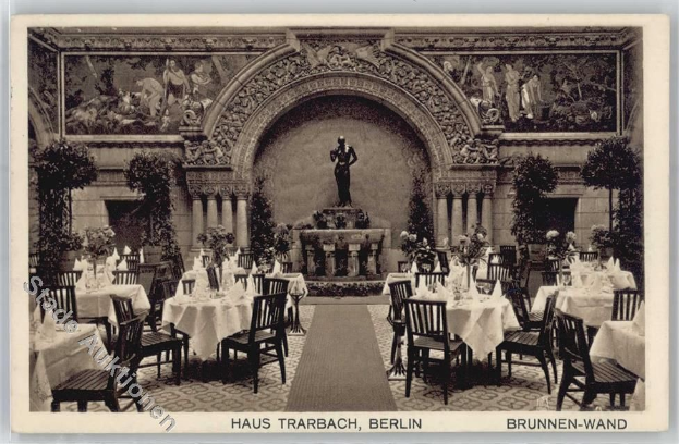 Ein altes Schwarz-Weiß-Foto eines Restaurants in Berlin, Deutschland, mit Tischen und Stühlen mit Blumenvasen, einer Statue im Hintergrund, Skulpturen und Pflanzen an den Wänden und Text am unteren Bildrand.