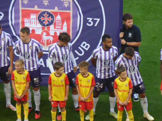 Gruppe junger Jungs in Chivas de Guadalajara Trikots auf einem Fussballfeld mit einem Teambanner im Hintergrund.