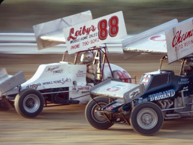 Mehrere Autos fahren auf einer Straße mit einer Sicherheitsbarriere im Hintergrund, mit einem unscharfen Hintergrund.