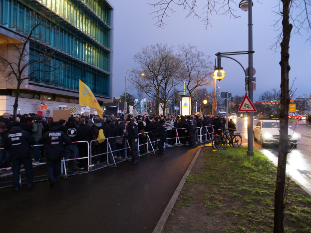 Große Menschenmenge protestiert vor einem Gebäude in Berlin und hält Schilder mit Barrikaden und Fahrrädern im Vordergrund.