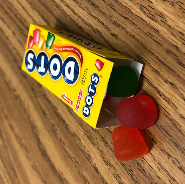 Eine Schachtel mit der Aufschrift "Punkt" gefüllt mit bunten Gummibären auf einem hölzernen Tisch.