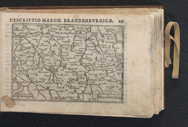 Ein aufgeschlagenes Buch mit einer detaillierten Karte der geografischen Merkmale Brandenburgs auf schwarzem Hintergrund.