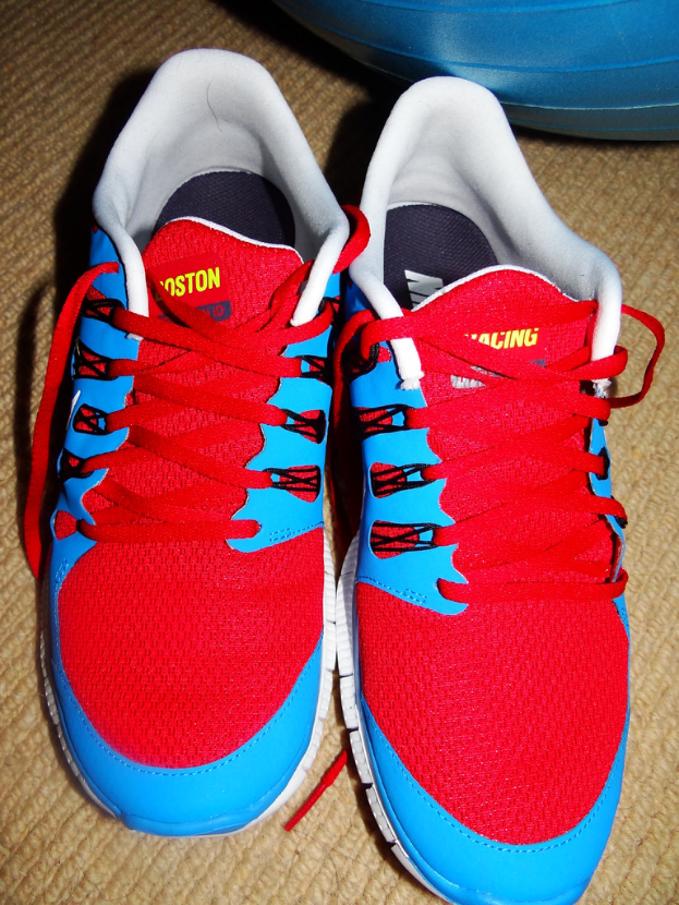 Ein Paar roter und blauer Schuhe mit Text darauf, vor einem unbestimmten Objekt positioniert.