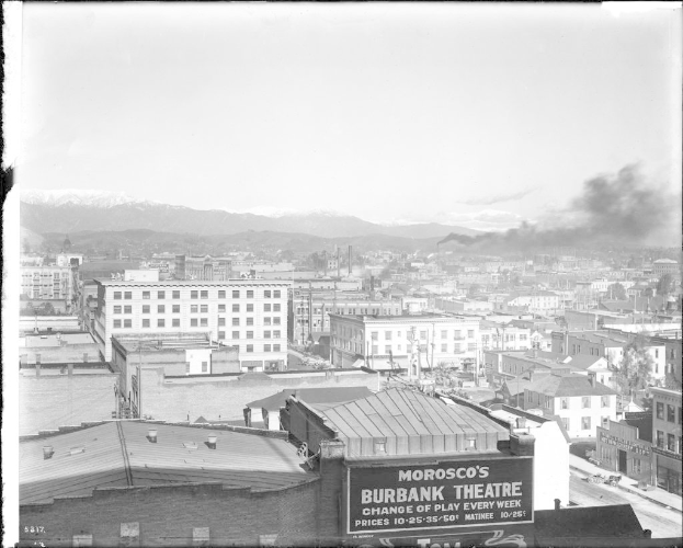 Ein Schwarz-Weiß-Bild einer Fabrik mit Rauch, der aus ihrem Schornstein aufsteigt und von Gebäuden umgeben ist.