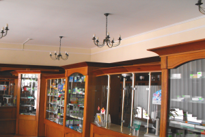 Ein Apothekeninneres mit hölzernen Schränken, die mit Medikamenten gefüllt sind und von der Decke hängenden Kronleuchtern, die gut sortiert und organisiert erscheinen.