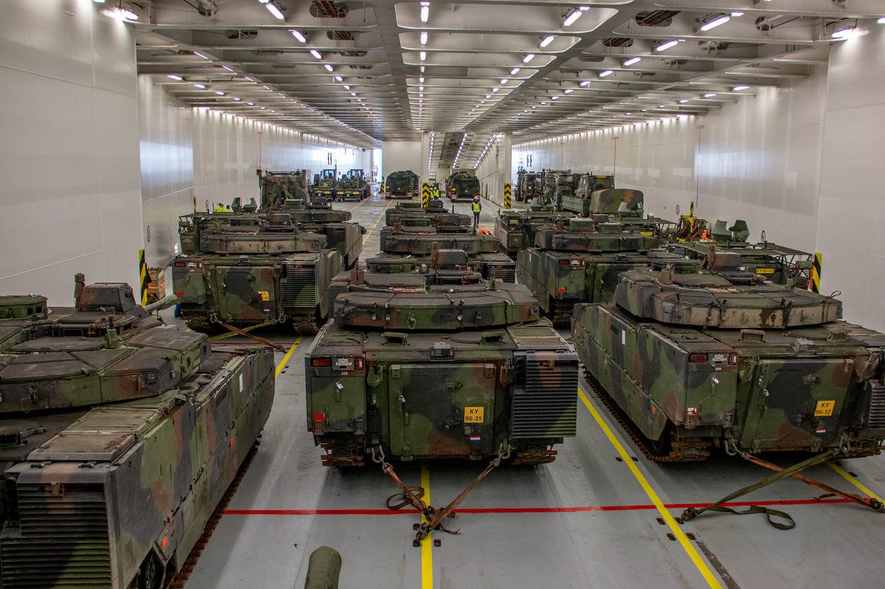 Ein grosser Militaraerraum mit Reihen von Militaraerfahrzeugen, Wanden auf beiden Seiten und Deckenbeleuchtung.