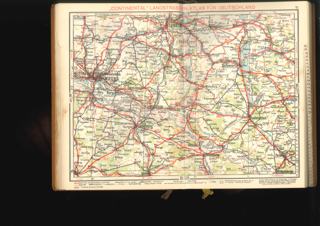 Ein aufgeschlagenes Buch mit einer detaillierten Deutschlandkarte mit Straßen und Autobahnen auf einem dunklen Hintergrund.