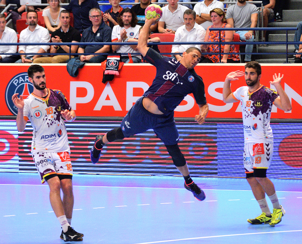 Männer spielen Handball auf einem Court mit einem Ball in der Mitte, Zuschauern im Hintergrund und einem Banner mit der Aufschrift "Futsal-Weltmeisterschaft 2015 - Paris Saint-Germain vs. Olympique Lyon".