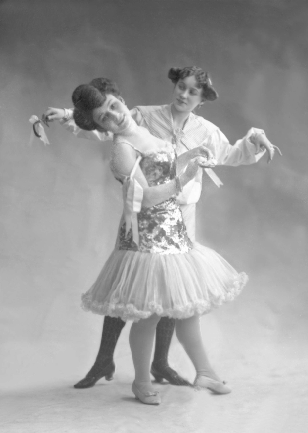 Zwei Frauen tanzen synchron, eine hält ein Band in einer alten Schwarz-Weiß-Fotografie.