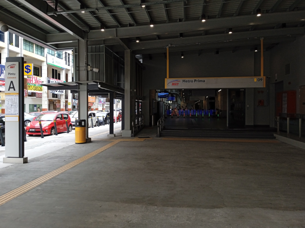 Leeres Parkhaus mit parkenden Autos, Betonpfeiler, Informationsschilder, Deckenleuchten und Gebäuden mit Fenstern im Hintergrund.