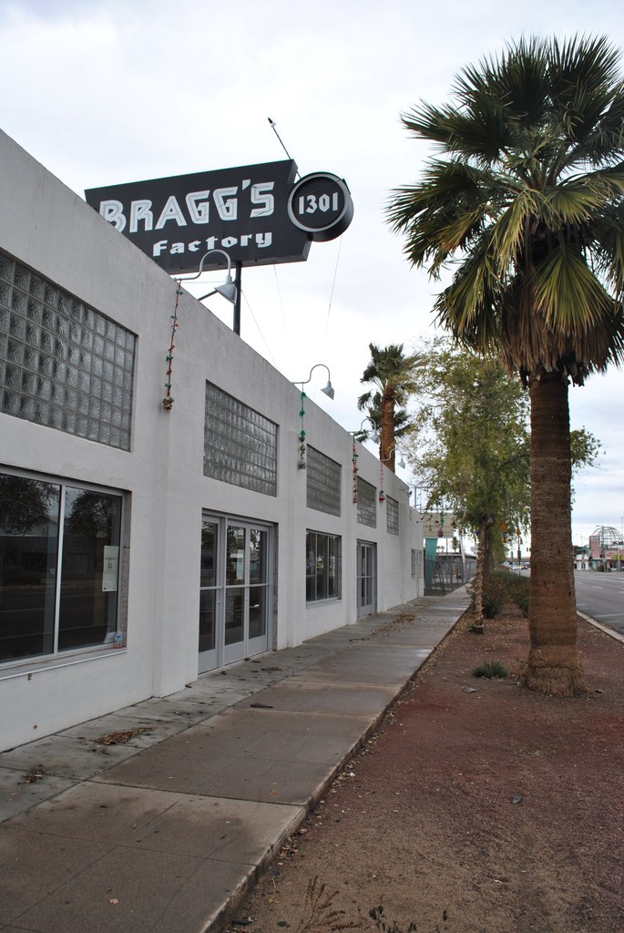 Ein Gebäude mit einer Fahne, auf der "Braggs Factory" steht, umgeben von Bäumen.