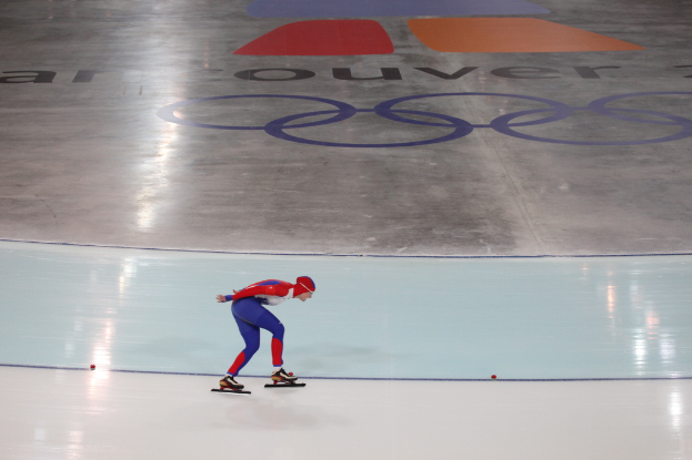 Eine Person in einem roten und blauen Kleid fährt auf einer weißen Fläche mit Text auf einem grauen Hintergrund.
