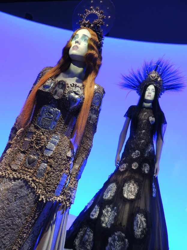 Zwei Schaufensterpuppen in verschiedenen Kleidern und Kopfbedeckungen.