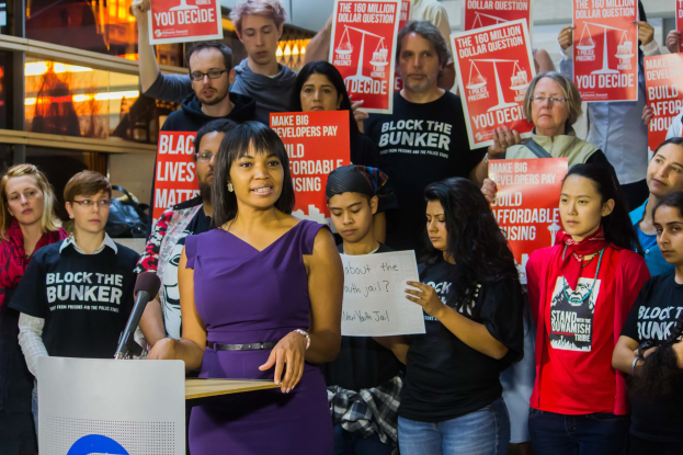 Eine Black Lives Matter-Aktivistin spricht in ein Mikrofon zu einer Menge mit Schildern.