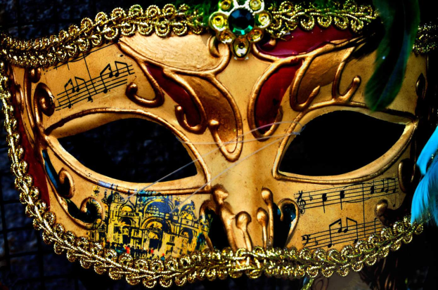 Ein Nahaufnahme eines Faschingsmasken mit Musiknoten, detaillierten Verzierungen und Federn im Hintergrund.
