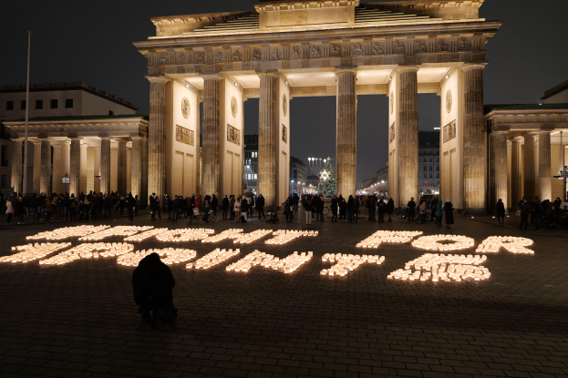 Eine Gruppe von Menschen steht vor dem beleuchteten Brandenburger Tor in Berlin, Deutschland, mit den Worten "Kämpfe für die Freiheit" auf dem Boden im Vordergrund.