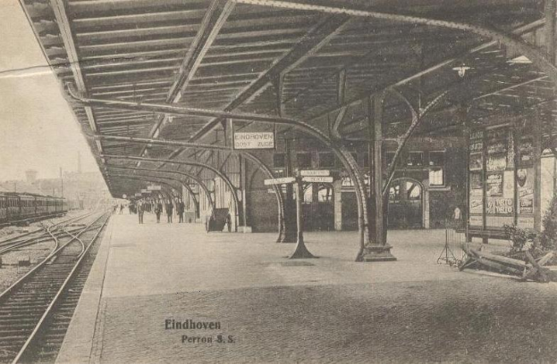 Schwarzes und weißes Foto einer Bahnsteig-Plattform mit Menschen, Bahnschienen, einem Zug, Gebäuden und Himmel, beschriftet mit 'Eindhoven Post Office, Berlin, Germany' unten.
