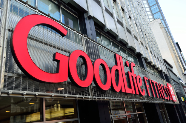 Außenansicht eines Goodlife Fitness Studios in New York City mit Glaswänden und einem Namensschild, umgeben von anderen Gebäuden und dem Himmel im Hintergrund.