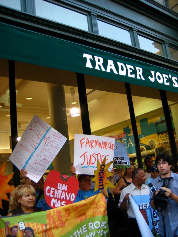 Eine Gruppe von Menschen steht vor einem Geschäft und hält Schilder und Plakate in den Händen.