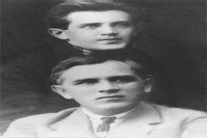 Zwei Männer in Anzügen und Krawatten posieren für ein Schwarz-Weiß-Foto vor einem dunklen Hintergrund, mit Text unten lesend "Gustav Klimt und sein Sohn, William Klimtz".