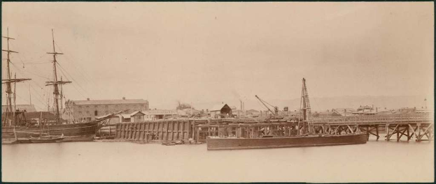 Eine Szene mit Wasser, Booten, Gebäuden, Strommasten, und einem Himmel.