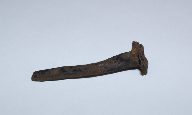 Ein verrosteter Eisen Nagel auf einer weißen Oberfläche.