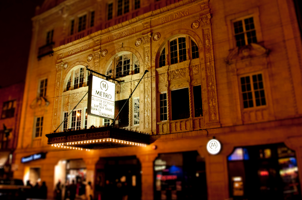 Ein gelbes Gebaude mit Geschaften unten, eines davon hat ein weisses Schild mit dem Wort "Metro" darauf.