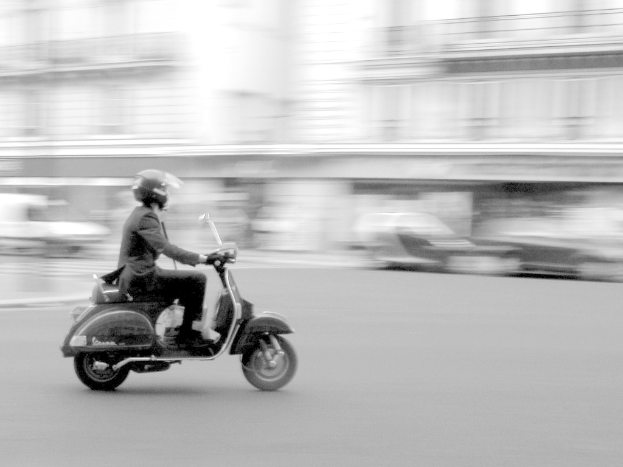 Eine Person, die auf der Straße ein Scooter fährt.