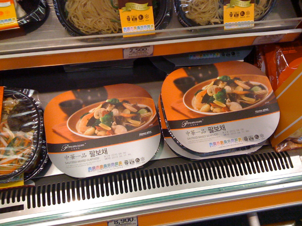 Lebensmittelboxen werden auf Regalen mit Preiszetteln präsentiert.