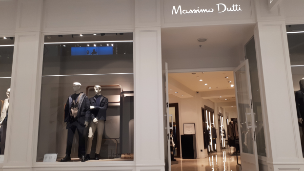 Innenansicht des Massimo Dutti-Geschäfts in Mailand, Italien, mit Schaufensterpuppen in aktueller Mode, beleuchteter Decke, Informationsschildern und sichtbarem Boden.