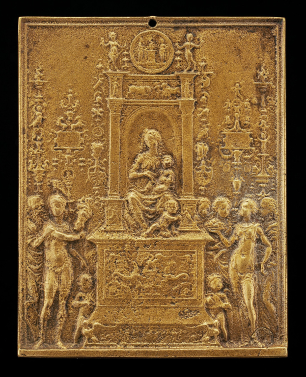 Goldene Plakette mit detaillierter Skulptur einer Frau in einem langen Kleid und eines Mannes in einem Anzug, eingerahmt von einem goldenen Rand, vor schwarzem Hintergrund.