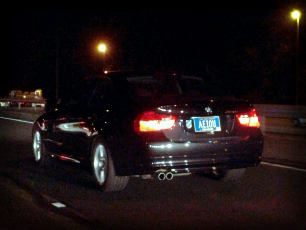 Ein schwarzes Auto mit Lichtern und einer Aufschrift ist in der Mitte einer Straße positioniert, mit einem schwarzen Hintergrund mit Lichtern.